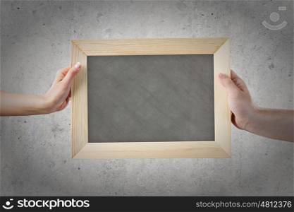 Blank frame. Close up of hands holding blank chalkboard