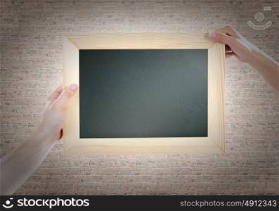 Blank frame. Close up of hands holding blank chalkboard