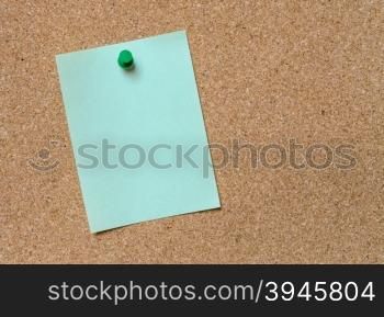Blank green paper posted on cork board with green tack pin for text and background