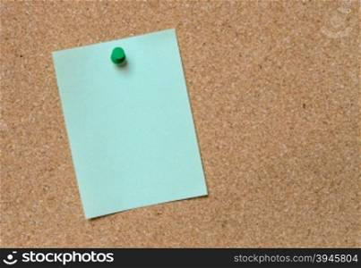 Blank green paper posted on cork board with green tack pin for text and background