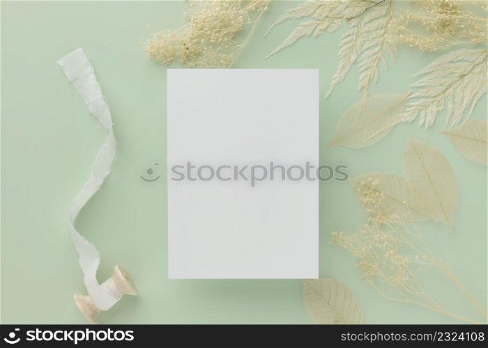 Blank greeting card invitation Mockup 5x7 on Brown envelope with dried flowers on pastel green background, flat lay, mockup