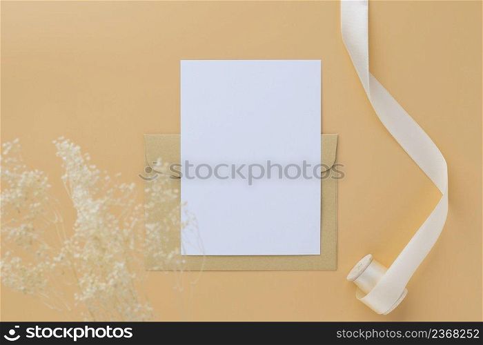 Blank greeting card invitation Mockup 5x7 on envelope with dry flowers and ribbon on paper background, flat lay, mockup 