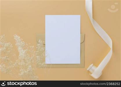 Blank greeting card invitation Mockup 5x7 on envelope with dry flowers and ribbon on paper background, flat lay, mockup 