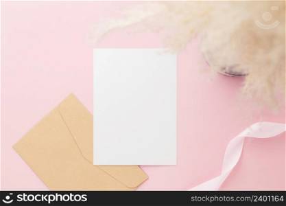 Blank greeting card invitation Mockup 5x7 on envelope with gypsophila flowers and ribbon on pink pastel paper background, flat lay, mockup