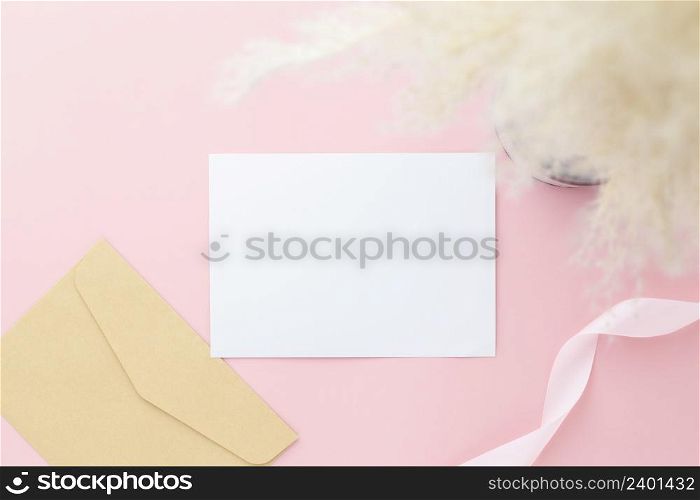 Blank greeting card invitation Mockup 5x7 on envelope with gypsophila flowers and ribbon on pink pastel paper background, flat lay, mockup