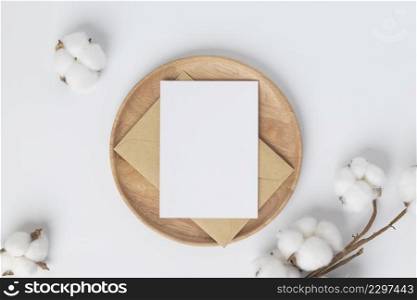 Blank greeting card invitation Mockup on Brown envelope with cotton flower on white background, Minimal table workplace composition, flat lay, mockup