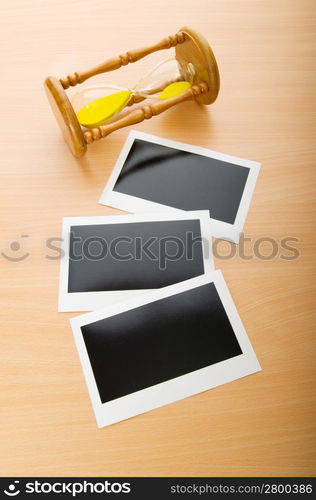 Blank instant photos and hour glass on the wooden table