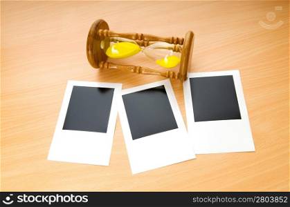 Blank instant photos and hour glass on the wooden table