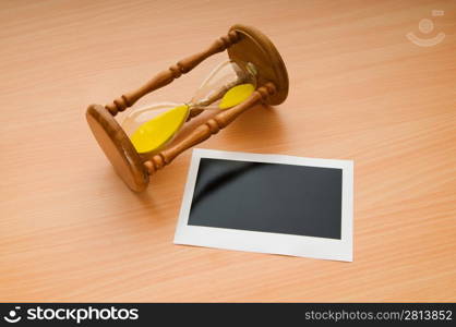 Blank instant photos and hour glass on the wooden table