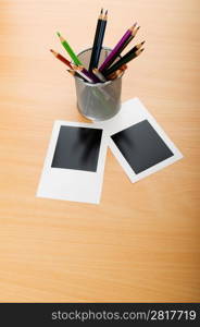 Blank instant photos and pencils on the wooden table