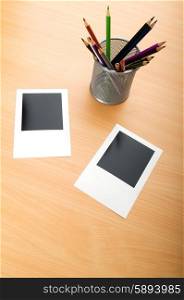 Blank instant photos and pencils on the wooden table
