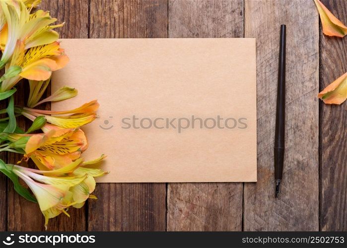 Blank invitation card with flowers and fountain pen on old wooden table still life