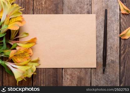 Blank invitation card with flowers and fountain pen on old wooden table still life