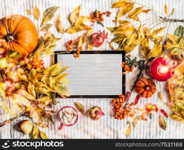Blank letter board styled with autumn arrangement: fall leaves, pumpkins, cup of cappuccino, burning candles, apples and rowan. Top view. Frame. Insta style. Cozy autumn composition. Flat lay