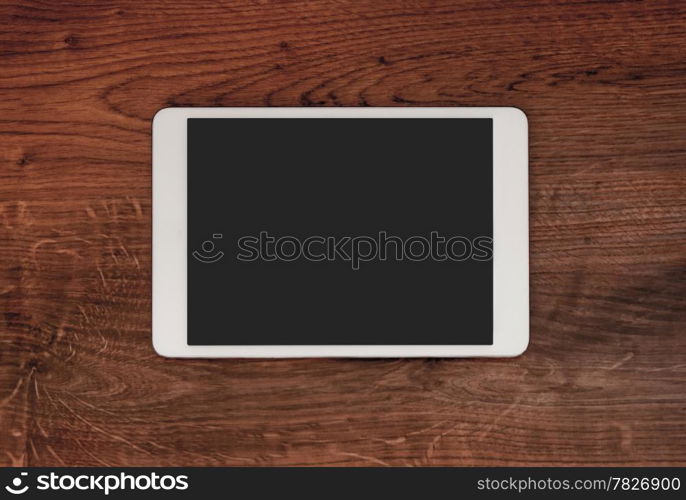 Blank modern digital tablet on a wooden desk. Top view. High quality.