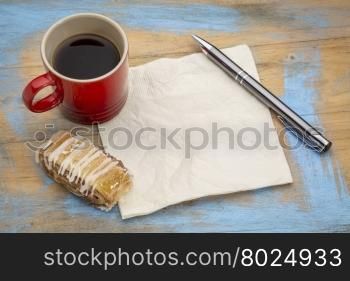 blank napkin with a pen,cup of espresso coffee and cookie against grunge painted wood