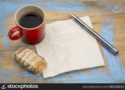 blank napkin with a pen,cup of espresso coffee and cookie against grunge painted wood