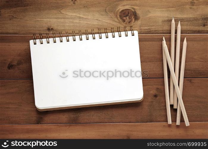 Blank note book and pencils on wood background, template with copy space for text