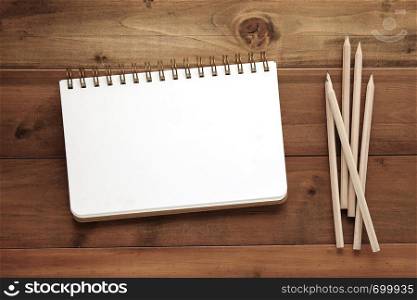 Blank note book and pencils on wood background, template with copy space for text