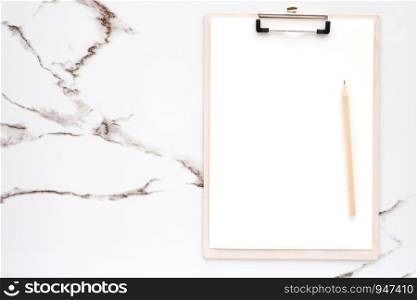 Blank note papers and pencil on clipboard on white marble background, with copy space for text, top view