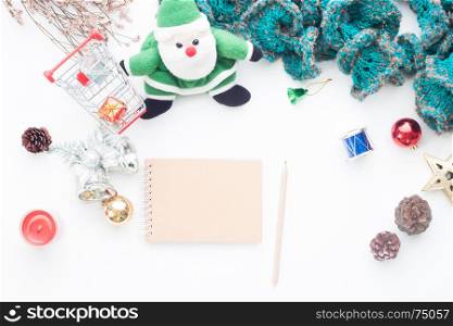 Blank notebook and pencil on white table with Christmas decorations and shopping cart, Top view