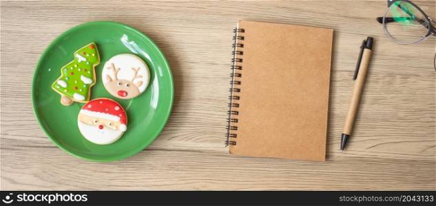 Blank notebook, black, Christmas cookies and pen on wood table, Top view and copy space. Xmas, Happy New Year, Goals, Resolution, To do list, Strategy and Plan concept