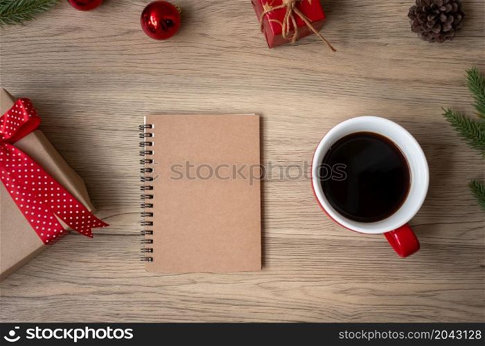 Blank notebook, black coffee cup and Christmas gift on wood table, Top view and copy space. Xmas, Happy New Year, Goals, Resolution, To do list, Strategy and Plan concept