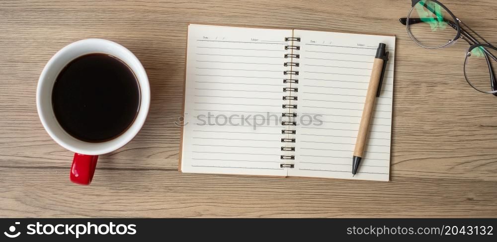 Blank notebook, black coffee cup and pen on wood table, Top view and copy space. Happy New Year, Goals, Resolution, To do list, Strategy and Plan concept