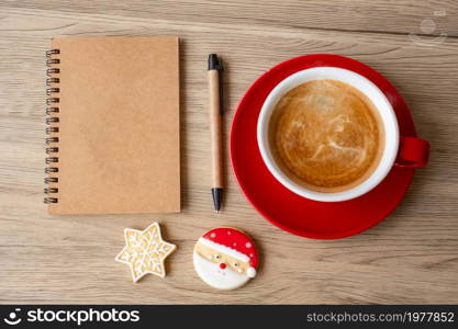 Blank notebook, black coffee cup, Christmas cookies and pen on wood table, Top view and copy space. Xmas, Happy New Year, Goals, Resolution, To do list, Strategy and Plan concept