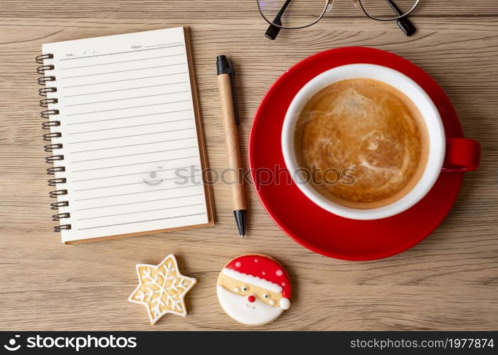 Blank notebook, black coffee cup, Christmas cookies and pen on wood table, Top view and copy space. Xmas, Happy New Year, Goals, Resolution, To do list, Strategy and Plan concept