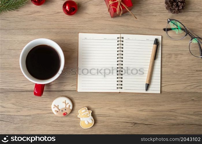 Blank notebook, black coffee cup, Christmas cookies and pen on wood table, Top view and copy space. Xmas, Happy New Year, Goals, Resolution, To do list, Strategy and Plan concept