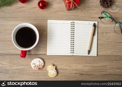 Blank notebook, black coffee cup, Christmas cookies and pen on wood table, Top view and copy space. Xmas, Happy New Year, Goals, Resolution, To do list, Strategy and Plan concept