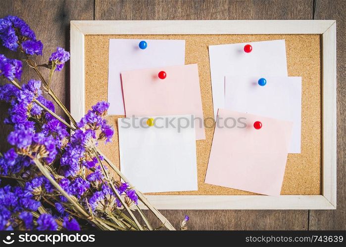 Blank notes on the cork board with dry flower bouquet,wooden background.