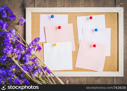 Blank notes on the cork board with dry flower bouquet,wooden background.