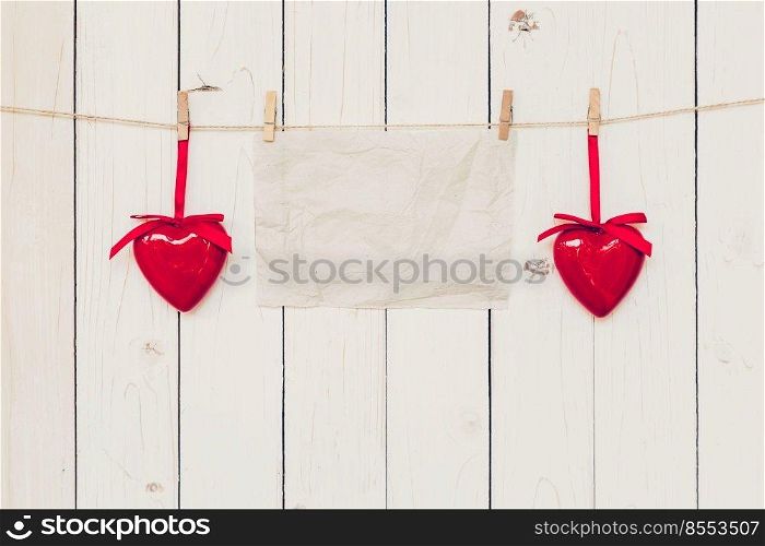 Blank old paper and red heart hanging on wood board background with space.