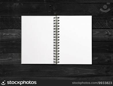 Blank open spiral notebook mockup isolated on black wood background. Blank open spiral notebook isolated on black wood background