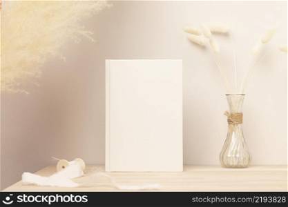 Blank paper card, greeting card mock up. decoration with dried Bunny Tail and pampas grass, Front view, Beautiful Bunny Tail grass in vase on wood table and beige cement wall background