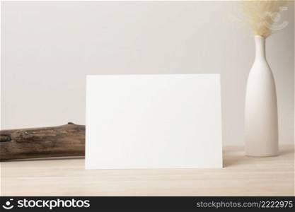 Blank paper card, greeting card mock up. decoration with dried Bunny Tail, Front view, Beautiful Bunny Tail grass in vase on wood table and beige cement wall background