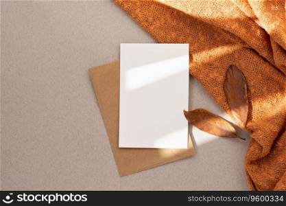 Blank paper card mock up, envelope, brown fall leaves, orange knitted textile on neutral beige background with aesthetic sun light shadow, autumn business branding template, wedding invitation design. Blank paper card mock up, envelope, brown fall leaves, orange knitted textile on neutral beige background with aesthetic sun light shadow. Autumn business branding template, wedding invitation design