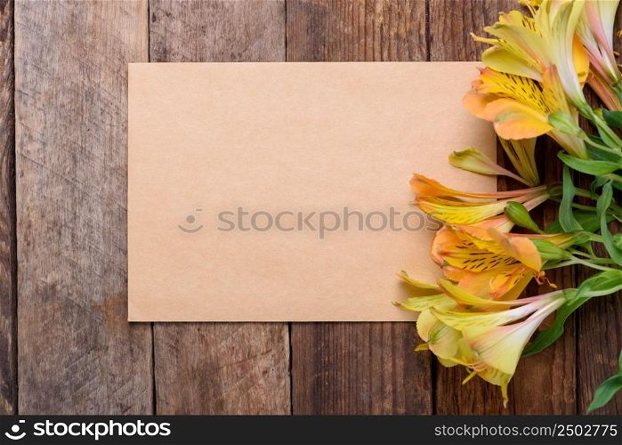 Blank paper card with lily flowers on old wooden table still life