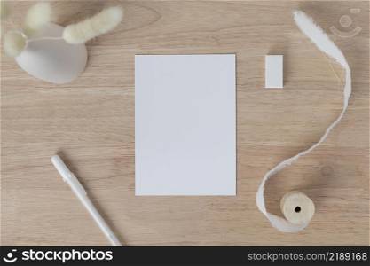 Blank paper cards, Blank greeting card invitation Mockup with Dried Bunny Tail grass in vase on a wood table, wood desk background, Minimal wood table workplace composition, flat lay, mockup