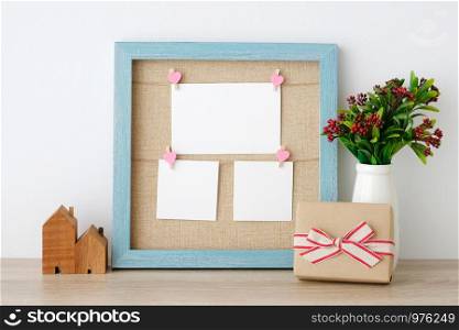 Blank paper cards hanging on blue vintage wooden frame and gift box on table background, copy space for text, aniversary, happy birthday and invitation card