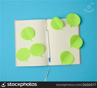 blank paper green stickers in the shape of a cloud glued to white sheets of a notebook, blue background