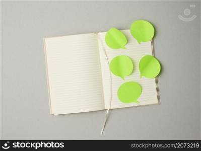blank paper green stickers in the shape of a cloud glued to white sheets of a notebook, gray background