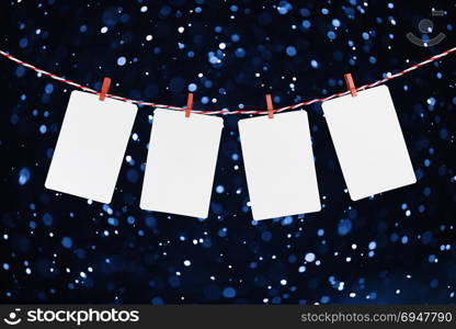 Blank paper or photo frames hanging on the red striped rope. Snowfall background, Template for your design. Blank paper or photo frames hanging on the red striped rope. Snowfall background, Template for your design.