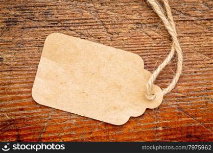 blank paper price tag with a twine against a rustic weathered wood
