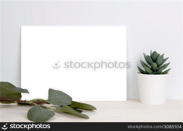 Blank paper sheet copy space with mockup and plants in potted on wooden table, poster and invitation with empty on desk, card decoration your design or branding, simplicity and minimal, nobody.