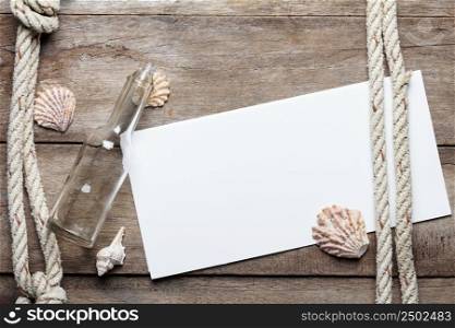 Blank paper sheet on weathered wood background with rope, shells, and bottle
