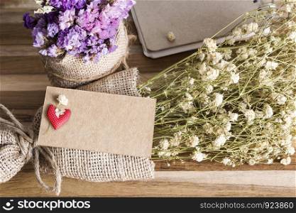 Blank paper tag and dry flowers on wooden background