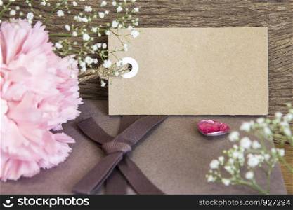 Blank paper tag with carnation flower on wooden background